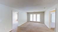 Located at 201 Eads Street in East Ridge, Tennessee, this single-floor residence offers a well-designed layout with a clean, functional aesthetic. The living area is generously proportioned, finished with soft, plush carpeting underfoot that adds warmth and comfort to the space. A standout feature is the set of French doors, which bathe the room in abundant natural light while providing direct access to the outdoors. The neutral-toned walls complement the light palette throughout, creating a bright and airy atmosphere. A textured ceiling adds a subtle architectural detail overhead. The open passage connecting to the adjacent room enhances the sense of flow, making the floor plan feel connected and spacious. The overall ambiance is calm and inviting, with a move-in-ready appeal suited for a variety of living arrangements. The combination of natural light, neutral finishes, and practical carpeted flooring makes this East Ridge property a comfortable and versatile single-level home.