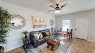 Located at 115 N Park Ct in Springtown, Texas, this well-appointed single-story home offers a thoughtfully designed open floor plan with warm, cohesive finishes throughout. The living room serves as the heart of the home, featuring wood-look flooring, a ceiling fan with light kit, and generous natural light streaming through blinds-covered windows. Earthy, eclectic décor accents the space with character and warmth.

The kitchen is a functional standout, boasting crisp white shaker cabinetry, granite countertops, a tile backsplash, stainless steel appliances, and a peninsula ideal for casual dining or food prep. Adjacent to the kitchen, the dining area is illuminated by an elegant wrought-iron chandelier and benefits from multiple windows that bring in ample daylight.

The bedrooms are carpeted for comfort, each equipped with ceiling fans and windows offering outdoor views of the surrounding landscape. The secondary bedroom includes a cozy seating nook, adding versatile functionality.

Both bathrooms are finished with granite-topped white vanities, wood-look tile flooring, and tub-shower combinations with clean white tile surrounds and brushed nickel fixtures. The overall design palette — neutral gray walls, natural wood tones, and granite accents — creates a cohesive, move-in-ready aesthetic throughout this inviting Texas home.