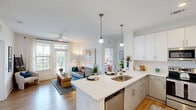 Located at 820 Clawson Pl in Fort Mill, SC, this thoughtfully designed 2-bedroom, 2-bathroom residence offers a modern and comfortable living experience across a single floor. The open-concept kitchen is a standout feature, boasting white shaker cabinetry extending to the ceiling, sleek white quartz countertops, stainless steel appliances, a subway tile backsplash, and a large center island with pendant lighting and bar seating — ideal for both cooking and casual dining. Light hardwood flooring flows throughout the main living areas, complementing the bright, neutral palette. The living room is bathed in natural light from large windows and a glass door, fitted with sheer curtains and wood blinds, and topped with a modern ceiling fan. Both bathrooms are well-appointed with wide vanities, white quartz countertops, framed mirrors, and direct access to spacious walk-in closets with wire shelving systems. The primary bedroom features plush carpet, generous natural light, and ample storage. The second bedroom is equally comfortable with soft carpeting and a large window. Clean lines, recessed lighting, and consistent modern finishes create a cohesive and inviting ambiance throughout this well-planned Fort Mill residence.