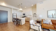 This single-story residence showcases a thoughtfully designed open-concept layout that seamlessly connects the kitchen and living areas. The kitchen is a standout feature, outfitted with two-tone cabinetry — crisp white upper cabinets paired with warm natural wood lower cabinets — complemented by white quartz countertops and a full suite of stainless steel appliances, including a refrigerator, range, microwave, and dishwasher. A central island with bar seating and pendant lighting overhead serves as both a functional workspace and a casual dining area. Wood-look flooring flows throughout the main living spaces, contributing to a warm, cohesive aesthetic.

The living area benefits from soaring ceilings and a large sliding glass door that invites abundant natural light. The bedrooms are carpeted for comfort, with generously sized windows featuring blinds, and one room includes a built-in window seat. Storage is well-addressed with a spacious walk-in closet fitted with shelving and hanging rods.

Two full bathrooms serve the residence; one features a soaking tub with shower combination, while the other offers a walk-in shower. Both bathrooms include wood-toned vanity cabinetry with white countertops and wood-look flooring, maintaining the home's consistent modern aesthetic throughout.