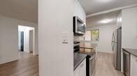 Located at 1903 Bayview Ave in Toronto's sought-after Leaside neighbourhood, this well-appointed 2-bedroom, 1-bathroom unit offers a thoughtfully designed single-floor layout. Light wood laminate flooring flows consistently throughout the space, complementing the crisp white walls and creating a bright, cohesive aesthetic.

The open-concept kitchen and living area serves as the heart of the unit. The kitchen features white shaker-style cabinetry, dark countertops, a subway tile backsplash, stainless steel appliances including a refrigerator, stove, and microwave, and a peninsula with additional counter space — ideal for casual dining or meal prep. The adjoining living area offers generous room for furniture arrangement.

The spacious primary bedroom is well-sized, with a window offering views of the surrounding greenery and a baseboard heating system. The second bedroom is comfortably proportioned with its own window and matching flooring. Both rooms are finished in neutral tones that maximize their bright, airy feel.

The bathroom is cleanly finished with large-format stone-look floor tiles, white subway tile surrounding a full soaker tub and shower, a grey vanity with white countertop, and chrome fixtures. A connecting hallway provides practical flow between all rooms in the unit.