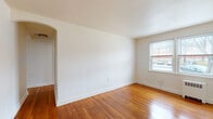 Located at 3906 Wabash Ave in Baltimore, MD, this single-floor unit offers a clean, functional layout with consistent design details throughout. Warm hardwood flooring flows through the living areas, bedrooms, and hallway, contributing to a cohesive and inviting atmosphere.

The living room is generously proportioned, featuring bright white walls, large windows that allow ample natural light, and a radiator heating unit beneath the sill. Street-facing views of the surrounding neighborhood are visible from multiple rooms. An arched doorway connects the living space to the hallway, adding a subtle architectural detail.

The bedrooms continue the hardwood flooring and include windows with blinds, closet access, and wall-mounted heating units. Natural light reaches each room comfortably.

The kitchen has been updated with gray shaker-style cabinetry, light countertops, a stainless steel sink, a stainless steel refrigerator, and a gas range. Light-toned flooring and a large window overlooking an exterior courtyard area complete the space.

The bathroom features white subway tile wainscoting, a soaking bathtub with an overhead shower, a vanity, and a window providing ventilation and natural light. Dark wood-look flooring grounds the room. A hallway connects all areas efficiently, maintaining a practical and organized flow throughout the unit.