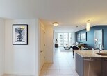 Located at 6055 NW 105 Ct in Doral, Florida, this well-appointed single-floor residence offers a thoughtfully designed open-concept layout with modern finishes throughout. The entryway leads seamlessly into the living and dining areas, where large floor-to-ceiling windows and a sliding glass door flood the space with natural light and provide views of the surrounding community. A bold teal accent wall anchors the living room, which features light-toned tile flooring and a private balcony beyond.

The contemporary kitchen is a standout, equipped with sleek dark cabinetry, stainless steel appliances including a range, microwave, and refrigerator, granite countertops, and track lighting overhead — ideal for both everyday cooking and entertaining.

The primary bedroom is a tranquil retreat with soft carpeting, a ceiling fan, and an ensuite bathroom nearby. A secondary bedroom offers corner windows with panoramic outdoor views and its own ceiling fan, creating a bright and airy atmosphere. A dedicated home office space provides a quiet nook with a window overlooking the exterior. The bathroom features a full tub-shower combination with clean white tile and built-in shelving for ample storage.