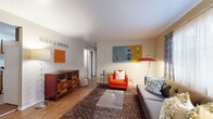 This single-floor residence offers a thoughtfully organized layout comprising a living room, bedroom, dedicated office, kitchen, hallway, and bathroom. The living room is an inviting space featuring warm hardwood-style flooring, a large area rug, and a natural light-filled window with patterned drapes. Bold, colorful artwork adorns the walls, complementing the eclectic mix of furnishings including a charcoal sofa and a vibrant orange accent chair.

The kitchen is efficiently designed with rich wood cabinetry, granite-style countertops, a white subway tile backsplash, and white appliances, offering ample workspace and storage. The bedroom provides a comfortable retreat with two closets offering generous storage, hardwood-style flooring, and soft neutral walls accented with decorative wall art. Natural light filters in through curtained windows, creating a calm and restful atmosphere.

The office area is a quiet, focused workspace featuring hardwood-style flooring and a framed landscape painting that adds a creative touch. The bathroom includes a full tub-shower combo, a warm wood vanity with a white countertop, and a large mirror. Throughout the residence, consistent hardwood-style flooring and a warm neutral palette create a cohesive and welcoming ambiance.