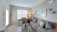 This single-floor residence offers a thoughtfully designed layout that balances comfort and functionality across its key living spaces. The entryway greets visitors with warm hardwood flooring, decorative wall art, and a bench, setting an inviting tone for the rest of the home.

The living room features a mix of hardwood and carpet flooring, neutral taupe walls, and large windows with horizontal blinds that allow generous natural light. The space comfortably accommodates a sofa, accent chair, and coffee table, creating an ideal gathering area.

The kitchen is outfitted with rich dark cabinetry, granite countertops, stainless steel appliances including a gas range, microwave, and refrigerator, along with hardwood flooring and recessed lighting. A peninsula counter provides additional prep and dining space.

Both bedrooms are carpeted and bright, each benefiting from multiple windows. The primary bedroom features an en-suite bathroom with a dual-sink vanity, granite countertops, dark cabinetry, and hardwood flooring. A second full bathroom mirrors this design with similar finishes. The consistent neutral palette with teal accents ties the entire residence together cohesively.
