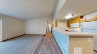 Located at 2129 Maltby Rd in Bothell, WA, this single-floor, 3-bedroom, 2-bathroom residence offers a practical and well-organized layout. The open-concept living and kitchen area forms the heart of the home, where a peninsula-style kitchen counter separates the two spaces. The kitchen is equipped with warm wood cabinetry, white appliances including a refrigerator, microwave, and range, and durable wood-look flooring that extends through the cooking area. The living room features soft carpeting, neutral walls, and a sliding glass door that allows natural light to fill the space and provides outdoor access. Each of the three bedrooms is carpeted and finished with neutral tones and rich wood baseboards. The primary bedroom is a comfortable size and is accompanied by a dedicated walk-in closet with wire shelving for organized storage. One bedroom includes a window with views of the surrounding neighborhood greenery. Both bathrooms are clean and functional, each featuring a full tub-and-shower combination with chrome fixtures. The primary bath includes a wood-toned vanity with an integrated sink and wood-look tile flooring. Throughout the home, consistent use of warm wood accents, neutral color palettes, and carpeted living spaces creates a cohesive and inviting atmosphere.