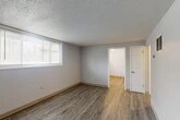 Located at 138 Jamesville Ave in Syracuse, NY, this 2-bedroom, 1-bathroom unit offers a practical and functional layout across a single floor. Wood-look luxury vinyl plank flooring runs throughout the space, complemented by neutral gray walls, white trim, and a textured popcorn ceiling that adds character to each room.

The spacious primary bedroom is the largest room in the unit, featuring a wide window with horizontal blinds that allows ample natural light to fill the room. Two closets provide solid storage solutions. The second bedroom is a comfortable size, also featuring a window with blinds and a floor vent for climate control.

The living area includes a built-in shelving unit and direct access to the unit's entrance, making for a welcoming and organized common space. The kitchen is equipped with warm oak cabinetry, a stainless steel sink with ample counter space, and a full-size refrigerator, along with a window that brightens the cooking area.

The bathroom features a full tub-and-shower combination with floor-to-ceiling tiled surround in a classic grid pattern. The 3D floorplan reveals a compact, efficiently arranged layout that maximizes the use of every square foot in this well-maintained unit.