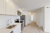 Located at 315 Anacostia Rd SE in Washington, DC, this single-floor, 3-bedroom, 1-bathroom residence offers a clean, modern design throughout. The open-concept living, dining, and kitchen area serves as the heart of the home, featuring crisp white shaker-style cabinetry extending to the ceiling, light quartz countertops, and a full suite of stainless steel appliances including a refrigerator, electric range, built-in microwave, and dishwasher. Recessed lighting illuminates the space, which flows seamlessly into the living and dining areas. Light wood-style plank flooring runs consistently throughout, creating a bright and cohesive aesthetic. A central hallway connects the three bedrooms, each finished with white walls and windows that allow natural light to filter in. Several bedrooms include closets with louvered or paneled doors, and the unit features a total of four closets for generous storage. The full bathroom is finished with large-format neutral tile surrounding a soaking tub and shower combination, complemented by chrome fixtures. A dedicated laundry area adds everyday convenience. The unit's bright, neutral palette and modern finishes create a fresh, move-in-ready living environment.