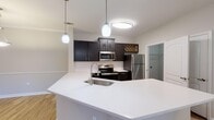 Located in North Charleston, SC, this single-floor residence offers a thoughtfully designed open-concept layout that seamlessly connects the kitchen, dining, and living areas. The kitchen is a standout feature, equipped with stainless steel appliances including a refrigerator, electric range, and microwave, complemented by rich dark cabinetry, a white quartz peninsula with an undermount sink, and stylish pendant lighting that adds a modern touch. A decorative wine rack accent adds character to the upper cabinetry.

The open living and dining area is bathed in natural light and features warm hardwood-style flooring that flows throughout the space. Crown molding lines the ceilings, lending an elegant finish, while French doors lead to an outdoor balcony, extending the living space outdoors.

The bedrooms are well-proportioned, each featuring hardwood-style flooring, ceiling fans, and windows dressed with blinds for natural light and privacy. The bathrooms are clean and functional, offering dark-toned vanity cabinetry with white quartz countertops and full tub-shower combinations. A walk-in closet provides generous storage. The overall aesthetic is modern and neutral, creating a bright, move-in-ready environment throughout.
