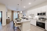 Located at 816 Addicks Howell Rd in Houston, TX, this thoughtfully designed one-bedroom, one-bathroom residence offers a contemporary open-concept layout with light wood-tone flooring and a neutral palette throughout. The combined dining and living area is bright and welcoming, anchored by French doors with floor-to-ceiling curtains that invite natural light and provide outdoor access. The kitchen is a standout feature, showcasing white shaker cabinetry, granite countertops, a white subway tile backsplash, stainless steel appliances, and a large island with bar seating — ideal for both cooking and entertaining. Pendant lighting adds a refined touch overhead. The bedroom is a serene retreat, comfortably sized with a large window framing greenery outside, ceiling fan, and access to multiple closets for generous storage. The bathroom features a dual-sink vanity with granite countertops, white cabinetry, a wide mirror with vanity lighting, and a separate water closet. Additional spaces include a dedicated entrance, hallway, and three closets, enhancing everyday functionality. The overall ambiance is clean, modern, and sophisticated — a well-appointed residence designed for comfortable urban living in West Houston.