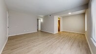 Located at 400 Cox Landing in Newport News, Virginia, this single-floor home offers a well-organized layout with a clean, modern aesthetic throughout. The main living area features light-toned luxury vinyl plank flooring and multiple windows fitted with horizontal blinds, allowing ample natural light to fill the space while offering views of surrounding greenery. Structural beams add a subtle architectural detail to the living area's ceiling, contributing to the room's character.

The kitchen is thoughtfully appointed with white cabinetry, granite-look countertops, and stainless steel appliances including a Whirlpool electric range with an overhead ventilation hood. The light wood-tone flooring continues seamlessly from the main living space into the kitchen, maintaining a cohesive flow.

The bedrooms are finished with plush, neutral-toned carpet and feature generous closet space, including double closets in at least one room, providing practical storage solutions. Windows bring in natural light and offer peaceful outdoor views.

The bathroom is finished with wood-look flooring, a white vanity, and a tub-shower combination with a crisp white curtain, maintaining the home's clean and neutral palette. Overall, the space presents a bright, move-in-ready environment with consistent finishes and functional design throughout.