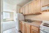 Located at 2120 University Ave in Madison, WI, this 2-bedroom, 1-bathroom apartment offers a practical and efficiently designed single-floor layout. The open kitchen features light wood cabinetry, a double-basin stainless steel sink, laminate countertops, and a full-size refrigerator. It flows naturally into the living area, which is carpeted and brightened by a large window with vertical blinds, a ceiling fan, and a wall-mounted air conditioning unit complemented by baseboard heating. The spacious primary bedroom is generously sized, featuring plush carpet, a wide picture window with vertical blinds, baseboard heating, and ample natural light. Both bedrooms include built-in closets with light wood sliding doors and shelving for organized storage. The second bedroom also benefits from a large window and similar carpeted finishes. The full bathroom is finished with tile flooring, a light wood vanity with a framed mirror, overhead lighting, and clean, neutral tones throughout. The unit's consistent use of warm wood tones, neutral walls, and carpeted living spaces creates a cohesive and functional atmosphere well-suited for comfortable everyday living near the University of Wisconsin–Madison campus.