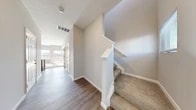 Located at 11 Woodford Way in Pataskala, Ohio, this two-story home offers a well-organized layout spread across two floors. The main level features an open-concept living, dining, and kitchen area filled with natural light. The kitchen is appointed with dark cabinetry, light stone-look countertops, stainless steel appliances including a refrigerator, range, and microwave, and a double-basin sink set within a functional island. A half bathroom with a dark vanity and hardwood-style flooring is conveniently located on this level, along with an entrance, hallway, and access to the attached garage. The garage features a tiled concrete floor, drywall-finished walls, an automatic door opener, and an electrical panel. The upper floor hosts the primary bedroom, which is generously sized with plush carpet, natural light from multiple windows, and a walk-in closet with wire shelving. Two additional bathrooms serve the upper level. A bonus room with carpet and ample natural light provides flexible use as an office or secondary living space. A dedicated laundry area and additional closet storage add further practicality. Throughout the home, neutral gray walls, textured ceilings, and consistent finishes create a clean, move-in-ready aesthetic.