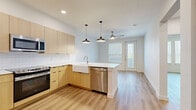 Located at Alamo Ranch Parkway in San Antonio, TX, this thoughtfully designed one-bedroom, one-bathroom unit offers a modern aesthetic throughout its efficient single-floor layout. Light hardwood flooring flows seamlessly across the entire space, enhancing the bright, airy atmosphere created by white walls and recessed lighting.

The open-concept kitchen is a standout feature, showcasing flat-front light wood cabinetry, white quartz countertops, a classic farmhouse sink, subway tile backsplash, and a full suite of stainless steel appliances including a range, microwave, dishwasher, and refrigerator. Stylish pendant lights hang above the kitchen peninsula, adding character to the space.

The living area transitions naturally from the kitchen and is illuminated by natural light from large windows and a sliding glass door that leads to a private balcony. A ceiling fan keeps the space comfortable year-round.

The bedroom is a well-proportioned retreat featuring dual windows, a ceiling fan, and access to a generous walk-in closet with built-in shelving and hanging rods. Additional closets throughout provide ample storage.

The bathroom is finished with modern light wood vanity cabinetry, a white quartz countertop, and a tub-shower combination clad in large-format gray tile. An in-unit laundry area completes this well-appointed home.