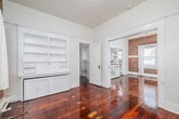 Located at 15 Paloma Ave in the vibrant Venice neighborhood of Los Angeles, this one-bedroom, one-bathroom residence offers a thoughtfully arranged single-floor layout. Rich, deeply toned hardwood floors run throughout the main living areas, lending warmth and a classic character to the space. Exposed brick walls serve as a striking architectural focal point in both the living room and bedroom, adding a distinctive industrial-meets-vintage charm.

The living room is bright and open, featuring a ceiling fan and natural light streaming through white-framed windows dressed with sheer curtains. A wide doorway connects the living area seamlessly to the bedroom, which benefits from multiple windows, an exposed brick wall, a classic radiator, and direct access to the outside via a private door. The bedroom also includes a dedicated closet for added convenience.

The kitchen is clean and functional, finished with white cabinetry, marble-style tile flooring, black-and-white tiled countertop accents, a gas range, and a full-size refrigerator. A window allows natural light to brighten the space. The bathroom completes the home's efficient layout. Throughout the residence, crisp white walls and trim provide a clean, neutral backdrop that complements the space's classic architectural details.
