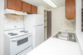 Located in Clinton Township, Michigan, this single-floor unit offers a straightforward and functional layout suited for comfortable everyday living. The main living area is generously proportioned, featuring warm beige carpeting underfoot and crisp white walls that create a bright, neutral backdrop. A ceiling fan with a light fixture provides both airflow and ambient lighting, while a large window invites natural light and outdoor views into the space.

The kitchen is positioned adjacent to the living area and is accessible via a pass-through opening that connects the two spaces. It is equipped with dark wood cabinetry, a white electric range, a refrigerator, and a sink with a countertop workspace. Tile flooring, a tiled backsplash, and under-cabinet lighting contribute to a clean and practical cooking environment.

The bedroom is a well-sized, carpeted room illuminated by a window with vertical blinds, offering a quiet and private retreat. An overhead light fixture with a ceiling fan adds to the room's functionality.

The bathroom features tile flooring in an earthy tone, a full-sized soaking tub with a white-tiled surround, a toilet, and a vanity with storage. The clean, white finishes throughout maintain a consistent, understated aesthetic across the entire unit.