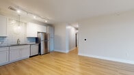 Located at 7008 Fordson Dr in Green, Ohio, this single-story home offers a thoughtfully designed layout across three bedrooms, two bathrooms, and three closets. Light hardwood flooring flows through the main living areas, creating a warm and cohesive aesthetic. The open-concept kitchen is a standout feature, boasting white shaker cabinetry, granite-look countertops, a blue subway tile backsplash, and a full suite of stainless steel appliances including a refrigerator, range, microwave, and dishwasher. Track lighting overhead enhances both functionality and ambiance. The adjacent living area is bright and spacious, offering a seamless transition between spaces. The primary bedroom is generously sized, with large windows that bring in natural light and views of the surrounding neighborhood, complemented by plush carpeting and a well-organized walk-in closet with wire shelving. Additional bedrooms are similarly carpeted and bright. Both bathrooms are finished with granite-topped vanities and framed mirrors; one features a sleek sliding glass walk-in shower, while the other includes a full tub-shower combination. Clean white walls and neutral tones throughout give the home a fresh, move-in-ready appeal.
