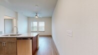 This 2-bedroom, 2-bathroom residence offers a thoughtfully designed single-floor layout that maximizes functionality and comfort. The open-concept kitchen serves as the heart of the home, featuring rich dark cabinetry, granite countertops, stainless steel appliances including a dishwasher and microwave, and a peninsula with an undermount sink — all flowing seamlessly into the living and dining area. Light wood-tone flooring runs throughout the unit, creating a warm and cohesive aesthetic. The living area benefits from natural light provided by double windows dressed with blinds, and is complemented by a ceiling fan with integrated lighting. The primary bedroom is a comfortable retreat with double doors leading to a dedicated closet and direct access to its own bathroom. The second bedroom is bright and clean, featuring the same light flooring and neutral walls, making it highly adaptable. Both bathrooms are finished with granite-topped vanities and warm wood cabinetry, maintaining a consistent design language. A hallway connects the private areas of the home efficiently. The overall palette of crisp white walls, warm wood floors, and brushed nickel hardware gives the space a clean, contemporary feel throughout.