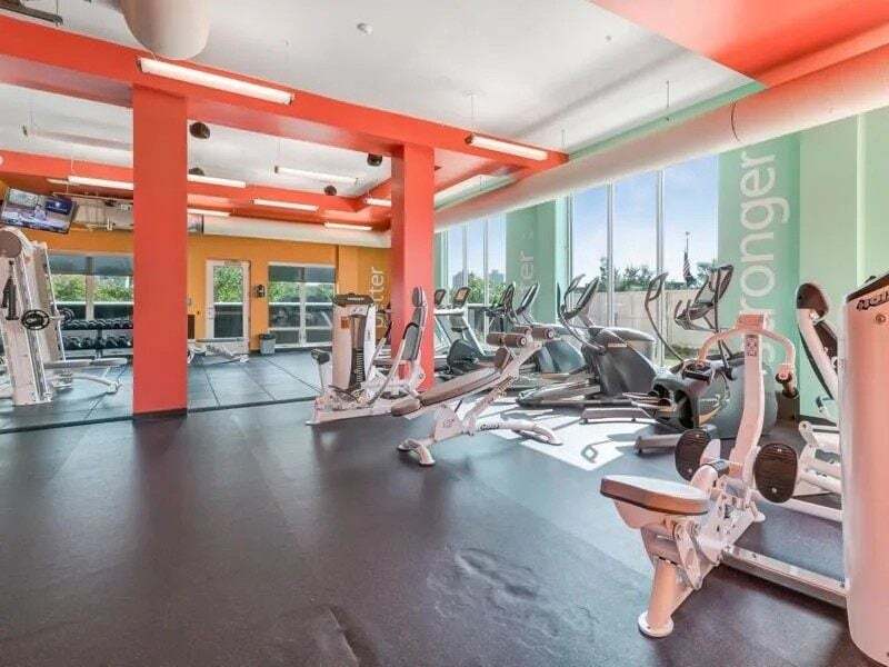 Interior of a modern apartment complex gym with cardio machines and weight equipment.