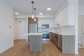 Located at 155 Greenbrier Rd in Cambridge, Ontario, this well-appointed 3-bedroom, 2-bathroom unit offers a thoughtfully designed single-floor layout with a clean, contemporary aesthetic. Light-toned hardwood flooring runs throughout the main living areas, complementing the bright white walls and modern trim.

The open-concept kitchen and living area forms the heart of the unit. The kitchen is equipped with stainless steel appliances including a refrigerator, range, microwave, and dishwasher. Two-tone cabinetry featuring wood-grain lower cabinets and white upper cabinets is paired with a white quartz countertop. A central island with pendant lighting above provides additional prep space and casual seating. The adjoining living area benefits from a large sliding window that fills the room with natural light and offers outdoor views.

The primary bedroom is a comfortable, well-sized room, while the two additional bedrooms feature large windows with exterior views and ample natural light. One bedroom includes a double-door closet for added storage.

The two bathrooms are finished in a neutral palette. The main bathroom features a sleek sliding-glass enclosed shower with warm tile surround, a wood-vanity with white countertop, and recessed lighting. The second bathroom offers a full soaker tub with tiled surround. A dedicated closet provides additional storage within the unit.