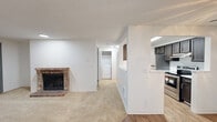 Located in Seattle, WA, this 1-bedroom, 1-bathroom unit offers a thoughtfully designed single-level layout that makes efficient use of its cozy footprint. The combined kitchen and living room serves as the heart of the home, where a classic brick fireplace anchors the living area, adding warmth and character to the carpeted space. A sliding glass door leads to a private balcony that overlooks lush, mature evergreen trees, bringing a sense of natural tranquility to everyday living. The kitchen is well-equipped with dark espresso cabinetry, light stone countertops, stainless steel appliances including a range and refrigerator, and wood-look flooring that extends throughout the cooking area. A skylight overhead fills the kitchen with natural light. A dedicated hallway leads to the bedroom, closet, bathroom, and an in-unit laundry area with a full-size washer and dryer. The bedroom features plush carpeting, a window with tree views, a baseboard heater, and direct access to a spacious closet. The full bathroom is finished with wood-look flooring, a dark vanity with stone countertop, and a tub-shower combination. Clean white walls and textured ceilings are consistent throughout, creating a bright and neutral canvas.