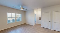 Located in Harvest, Alabama, this single-floor, one-bedroom, one-bathroom home offers a well-organized layout with modern finishes throughout. The open-concept living and kitchen area is anchored by a large granite-topped island with an undermount sink and pendant lighting, providing both prep space and a natural gathering point. The kitchen features gray shaker-style cabinetry, matching granite countertops, stainless steel refrigerator, and black appliances including a range and built-in microwave. Light wood-look flooring extends throughout the main living areas, complementing the neutral, bright wall tones. The living room is bathed in natural light from a large window and is equipped with a ceiling fan. The bedroom offers plush carpeting, dual windows overlooking the outdoors, and a ceiling fan, with direct access to a dedicated laundry room equipped with a full-size washer and dryer and wire shelving. The bathroom features gray vanity cabinetry with granite countertops, a single undermount sink, and light wood-look flooring. Clean white doors and trim, recessed lighting, and a consistent neutral palette lend a cohesive, move-in-ready feel to this efficiently designed home.