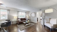 Located at 4440 Roanoke Pkwy in Kansas City's vibrant Roanoke neighborhood, this well-designed one-bedroom, one-bathroom residence offers a thoughtful layout that maximizes every square foot. Rich hardwood flooring flows throughout the main living areas, anchoring a bright and open living room that features a large window with decorative curtains, a textured ceiling, and neutral gray walls that create a versatile backdrop. A hallway with a built-in shelving unit and a chalkboard wall accent adds both functionality and character to the entryway area. The kitchen is equipped with dark espresso cabinetry, white countertops, stainless steel appliances, and a striking mosaic tile backsplash, complemented by light wood-tone flooring. A peninsula counter opens to a dining area, enhancing the open feel. The bedroom offers plush carpeting, a ceiling fan, and natural light through white-curtained windows, providing a calm and restful retreat. The bathroom features clean subway tile surrounds in the tub-shower combination, brass fixtures, and a window for natural ventilation. Throughout, the space maintains a cohesive, modern aesthetic with warm and neutral tones.