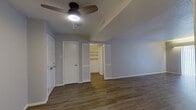 This single-floor residence offers a practical and well-organized layout, housing three bedrooms, two bathrooms, a living room, and a kitchen within a efficiently arranged floor plan. Wood-style plank flooring runs consistently throughout the unit, providing a cohesive look, while neutral gray and beige tones on the walls contribute to a clean, understated aesthetic.

The living room receives natural light through a large window fitted with horizontal blinds, and features medium-toned hardwood-style flooring. The kitchen is designed in a galley configuration, lined with white cabinetry, white countertops, and white appliances including a refrigerator, electric range, and dishwasher, maximizing storage and workspace efficiency.

The spacious primary bedroom includes louvered closet doors, access to a walk-in closet with built-in shelving, and a ceiling fan with light fixture. The two secondary bedrooms are modest in size, each featuring light wood-style flooring and windows for natural light. Both bathrooms are similarly appointed, featuring dark granite-topped vanities with dark wood cabinetry, tub-shower combinations with white tile surrounds, and wood-style flooring.