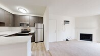 Located on Mast Boulevard in Santee, California, this single-story unit offers a well-designed layout with contemporary finishes throughout. The kitchen serves as a functional centerpiece, featuring dark wood-toned cabinetry, white quartz countertops, a peninsula with an undermount sink, and a full suite of stainless steel appliances including a refrigerator, electric range, and built-in microwave. Light wood-style flooring runs through the kitchen and entry areas, providing a clean, modern aesthetic.

The living area is carpeted and connects directly to a private balcony through a sliding glass door, offering views of surrounding greenery. A wall-mounted AC unit provides climate control in this space. The bedrooms are also carpeted and equipped with ceiling fans and windows that bring in natural light. One bedroom features dual closets, offering generous storage, while additional bedrooms include sliding mirrored closet doors.

The bathrooms are updated with white quartz vanity surfaces, dark wood-toned cabinetry, and chrome fixtures. One bathroom includes a walk-in glass-enclosed shower, while another features a shower-tub combination. The overall ambiance of the unit is clean, bright, and move-in ready, with a neutral color palette throughout.