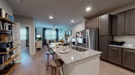 This single-floor residence showcases a thoughtfully designed open-concept layout where the kitchen flows seamlessly into the living and dining areas. The kitchen is a standout feature, equipped with dark espresso cabinetry, granite countertops, a subway tile backsplash, and a full suite of stainless steel appliances including a refrigerator, range, microwave, and dishwasher. A central island with an undermount sink and bar seating provides additional prep space and casual dining options.

The living area is bright and functional, featuring recessed lighting, a ceiling fan, and large windows with blinds that allow natural light to filter through. A dedicated workspace area with wall-mounted shelving adds versatility to the living space. Wood-look plank flooring runs consistently throughout, adding warmth and cohesion.

The bedroom is comfortably sized, with a ceiling fan, a large window, and direct access to the bathroom. The bathroom includes a tub-shower combination with white subway tile surround and connects directly to a walk-in closet with built-in shelving and hanging rods, offering practical storage solutions throughout the residence.