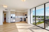 Located at 4465 Griffin Rd in Hollywood, FL, this modern 2-bedroom, 2-bathroom residence offers a well-designed open-concept layout filled with natural light. Light wood flooring flows throughout the space, complementing the clean white walls and contemporary finishes.

The combined living, dining, and kitchen area serves as the heart of the home. The kitchen is outfitted with light wood cabinetry extending to the ceiling, a marble-style tile backsplash, stainless steel appliances including a side-by-side refrigerator, dishwasher, range, and microwave, as well as a sleek undermount sink. Floor-to-ceiling sliding glass doors lead to a private balcony, flooding the living area with sunlight and offering open outdoor views.

Both bedrooms are bright and airy, featuring large windows with views of the surrounding landscape. The primary bedroom offers a generous footprint with ample closet space. The unit includes four closets in total, providing excellent storage throughout.

The two bathrooms are finished with large-format marble-style tile, wood-toned vanities, and white quartz countertops. One bathroom features a glass-enclosed walk-in shower, while the other includes a soaking tub. Additional conveniences include in-unit laundry and a connecting hallway that ties the layout together efficiently.