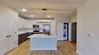 This contemporary townhouse in Elgin, IL offers 740 square feet of efficiently designed living space across two floors. The main level showcases an open-concept layout, combining the kitchen and living area. The kitchen is a highlight, featuring a sleek design with two-toned cabinetry - white upper cabinets and gray lower cabinets. It's equipped with stainless steel appliances, including a side-by-side refrigerator and built-in microwave. A large kitchen island with a sink serves as a focal point, complemented by a modern rectangular light fixture.

Natural light floods the space through large windows, enhancing the airy feel of the home. The living area, adjacent to the kitchen, offers ample space for relaxation and entertaining. Light-colored wood flooring runs throughout the main level, adding warmth to the contemporary aesthetic.

The bedroom, likely located on the upper floor, features plush carpeting and a spacious closet with double doors. The bathroom continues the modern theme with a floating vanity, large mirror, and necessary accessibility features. Throughout the home, recessed lighting and neutral wall colors contribute to the bright, fresh ambiance. This townhouse combines style and functionality, making efficient use of its 740 square feet to create a comfortable living space.