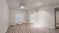 This single-floor residence features a clean, modern design highlighted by neutral warm-beige walls and light wood-look flooring in the main living areas. The open living room is generously sized, benefiting from two windows fitted with blinds that allow ample natural light, complemented by a ceiling fan and a track lighting fixture. A private entry door with a window panel provides direct access from this main space.

The kitchen is well-appointed with dark espresso-toned cabinetry, light quartz-style countertops, and a full suite of stainless steel appliances including a refrigerator, electric range, over-the-range microwave, and dishwasher. A window above the sink adds brightness to the workspace.

The bedrooms feature plush carpeting, ceiling fans with light fixtures, and blinds-covered windows. At least one bedroom includes a reach-in closet with built-in shelving. The bathrooms are finished with wood-look tile flooring, dark vanity cabinetry, light countertops, framed mirrors, and shower-tub combinations. A hallway connects the living area to the bedrooms and bathrooms, maintaining a functional and organized layout throughout the unit.