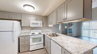 This contemporary townhouse in Lakewood, Colorado offers a spacious 990 square feet of living area spread across two floors. The home features two bedrooms, including a generous primary bedroom of 390 square feet, and two full bathrooms. The layout is efficiently designed with three closets for ample storage.

The kitchen is a highlight, boasting light-colored cabinetry, granite countertops, and modern white appliances. The open concept design creates a seamless flow between the kitchen and living areas. Light wood-look flooring throughout the main living spaces adds warmth and continuity.

Both bathrooms are updated with clean, white fixtures, granite vanity tops, and practical shower/tub combinations. The bedrooms feature plush carpeting and large windows that allow natural light to flood the spaces. One bedroom includes a unique architectural element with sloped ceilings, adding character to the room.

The townhouse's neutral color palette, predominantly in shades of white and light gray, creates a bright and airy atmosphere throughout. This modern and low-maintenance home is ideal for those seeking a turn-key property in a convenient Lakewood location.