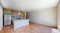 Located at 4745 40th Ave SW in Seattle's West Seattle neighborhood, this one-bedroom, one-bathroom unit offers a well-designed single-floor layout that makes efficient use of its space. The open-plan living and kitchen area is anchored by a striking central island with a granite countertop, double sink, and pendant lighting overhead. The kitchen is equipped with stainless steel appliances, including a refrigerator, range, and microwave, complemented by warm wood cabinetry, a mosaic tile backsplash, and track lighting. Hardwood floors extend throughout the main living area, adding warmth and continuity to the space. Large sliding glass doors in the living area open to a private balcony, allowing abundant natural light to pour in while offering a serene view of surrounding trees. The bedroom features plush carpeting, a ceiling fan, a wide window, and a closet, providing a comfortable and quiet retreat. The bathroom is clean and functional, complete with a tub-shower combination and hardwood flooring. The unit's neutral color palette and modern finishes create a bright, cohesive ambiance throughout.