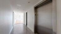 Located at 205 Church Street in the heart of New Haven, CT, this two-floor unit offers a thoughtfully designed layout spread across a generously proportioned main floor and a secondary upper level. The principal floor is dominated by a bright, open-plan living and kitchen area, where warm hardwood flooring extends throughout and large French doors flood the space with natural light while framing views of the surrounding cityscape. The kitchen features a sleek island with a dark countertop, pendant lighting, and white cabinetry, seamlessly integrated into the expansive living area. Bedrooms are well-sized, each finished with the same rich hardwood flooring and fitted with large windows dressed in classic blinds, ensuring ample natural light and urban views. Sliding panel doors provide elegant room transitions and generous closet access. The bathroom is finished to a high standard, with large-format marble-effect tiles, a glass-enclosed walk-in shower, and crisp white fixtures. A clean, modern hallway with large-format grey tile flooring provides access to a private elevator, adding a notable level of convenience. The upper level opens onto a spacious rooftop terrace, enclosed by a classic stone balustrade, offering panoramic views across the New Haven skyline—a distinctive and impressive outdoor amenity.