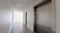 Located at 205 Church Street in the heart of New Haven, CT, this two-floor unit offers a thoughtfully designed layout spread across a generously proportioned main floor and a secondary upper level. The principal floor is dominated by a bright, open-plan living and kitchen area, where warm hardwood flooring extends throughout and large French doors flood the space with natural light while framing views of the surrounding cityscape. The kitchen features a sleek island with a dark countertop, pendant lighting, and white cabinetry, seamlessly integrated into the expansive living area. Bedrooms are well-sized, each finished with the same rich hardwood flooring and fitted with large windows dressed in classic blinds, ensuring ample natural light and urban views. Sliding panel doors provide elegant room transitions and generous closet access. The bathroom is finished to a high standard, with large-format marble-effect tiles, a glass-enclosed walk-in shower, and crisp white fixtures. A clean, modern hallway with large-format grey tile flooring provides access to a private elevator, adding a notable level of convenience. The upper level opens onto a spacious rooftop terrace, enclosed by a classic stone balustrade, offering panoramic views across the New Haven skyline—a distinctive and impressive outdoor amenity.