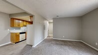 Located on Gunnerson Ave in Murfreesboro, Tennessee, this single-floor, one-bedroom, one-bathroom residence offers a practical and comfortable layout. The entrance opens into a combined living area finished with soft carpeting and neutral gray walls, creating a clean, move-in-ready atmosphere. A textured ceiling runs throughout the main living spaces, adding subtle character. The living area benefits from a full-width sliding glass door fitted with vertical blinds, allowing natural light to pour in while offering views of the surrounding greenery. The galley-style kitchen is positioned adjacent to the living area and features warm-toned wood cabinetry lining both walls, a light countertop with an integrated sink, and white appliances including a refrigerator, range, and dishwasher. Light wood-look flooring ties the kitchen together efficiently. The spacious bedroom is carpeted and includes a ceiling fan with a light fixture, a window for natural light, and direct access to a generous walk-in closet outfitted with dual hanging rods and shelving on both sides. The bathroom is well-appointed with a white vanity, a tiled shower-tub combination, and wood-look vinyl flooring, completing this thoughtfully designed residence.