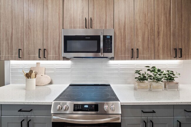 Elegantes gabinetes de cocina europeos de dos tonos con iluminación debajo de los gabinetes y cajones y puertas de cierre suave. - The Henslow Daniel Island Apartments & Tow...