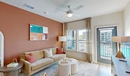 Located in Fort Myers, FL, this well-appointed 2-bedroom, 3-bathroom residence offers a thoughtfully designed single-floor layout with generous living space. The open-concept kitchen and living area serves as the heart of the home, featuring light wood-tone flooring, a kitchen island with bar seating illuminated by gold pendant lights, sleek light-wood cabinetry with gold hardware, stainless steel appliances, and a dedicated wine shelf. The living room showcases warm terracotta accent walls, large windows with sheer draping, a ceiling fan, and a private balcony door that frames outdoor views of the pool and surrounding community. The primary bedroom is a comfortable retreat with a ceiling fan, large windows with pool views, and easy access to the hallway. The second bedroom features a bold botanical-print accent wall, generous natural light, and a ceiling fan. Three full bathrooms serve the residence, including one with marble-tiled tub surround. Five closets — including a spacious walk-in — provide abundant storage, complemented by a dedicated laundry room. Light wood flooring flows consistently throughout the space, tying each room together into a cohesive, modern aesthetic ideal for comfortable Florida living.