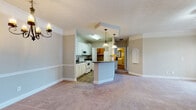 Located at 800 Gunn Rd in Centerville, Georgia, this single-floor home offers a well-designed layout with classic architectural details and functional living spaces. The open-concept living and dining area is finished with plush carpeting, crown molding, and a decorative chandelier, creating a warm and inviting atmosphere. A chair rail detail runs along the walls, adding a traditional touch to the space.

The kitchen is thoughtfully designed in a galley-style layout, featuring white cabinetry with dark countertops, wood-look flooring, and white appliances including a range, microwave, and refrigerator. Pendant lighting hangs above a peninsula that connects the kitchen to the living area, enhancing both function and flow. The kitchen also provides access to a utility area equipped with wire shelving, washer/dryer hookups, and a water heater.

The bedrooms are carpeted and generously proportioned, with neutral wall tones and natural light from windows with blinds. At least one bedroom includes a spacious walk-in closet with built-in shelving and hanging rods. The bathroom features a double-sink vanity with white cabinetry and gold hardware, a large framed mirror, wood-look flooring, and a full tub-shower combination, offering both style and practicality.
