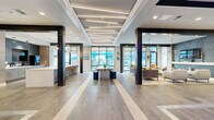 Located at 1701 Central Ave. in vibrant St. Petersburg, FL, this contemporary single-floor communal space offers a thoughtfully designed open-plan layout with distinct functional zones flowing seamlessly into one another. Large-format tile flooring runs throughout, complemented by bold dark structural columns that add an industrial character to the modern interior.

The main living area is anchored by a deep-toned accent wall and wall-mounted TV, surrounded by a curated arrangement of plush sofas and lounge chairs in neutral tones accented with warm pops of color. Floor-to-ceiling glass windows and sliding doors flood the space with natural light and provide direct views of the outdoor pool and surroundings.

A prominent bar-height counter with pendant globe lighting serves as a social hub, backed by warm wood cabinetry and dark tile, complete with bar seating ideal for casual gatherings or work sessions. Linear LED lighting strips on the ceiling add a modern, architectural touch near the entry.

A glass-enclosed private meeting or lounge room offers an intimate retreat, distinguished by vibrant painted brick walls, moody blue ambient lighting, and a round table with coral-toned seating — a creative and energetic contrast to the calmer main lounge. Together, these areas create a dynamic, welcoming environment designed for both socializing and productivity.