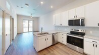 Located at 1602 Belt Line Road in Garland, TX, this thoughtfully designed one-bedroom, one-bathroom residence offers a clean, modern aesthetic throughout its single-floor layout. The open-concept kitchen serves as a central highlight, featuring crisp white cabinetry with matte black hardware, granite countertops, a peninsula with an integrated sink, and a full suite of stainless steel appliances including a refrigerator with ice maker, electric range, microwave, and dishwasher. Subway tile backsplash and recessed lighting complete the polished look. Wood-look flooring extends through the main living and kitchen areas, while the living space opens to a private balcony, allowing natural light to flow in. The bedroom is a comfortable retreat finished with soft carpet, a ceiling fan, and a window with exterior views. It connects directly to a well-organized walk-in closet outfitted with dual hanging rods and built-in shelving for ample storage. The bathroom is clean and functional, offering a white vanity with granite countertops, black hardware, and a tiled shower-tub combination. Elevated ceilings throughout the space contribute to an open, airy feel, making this residence feel welcoming and efficiently utilized.