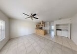 This single-story, 1-bedroom, 1-bathroom home offers a well-organized layout designed for comfortable everyday living. Light-toned ceramic tile flooring runs throughout the entire space, creating a clean, cohesive aesthetic from room to room.

The open-concept living and dining area is bright and airy, featuring a ceiling fan with light fixture and a large window that invites natural light into the space. The kitchen is a standout feature, centered around a peninsula-style breakfast bar with light wood cabinetry fitted with glass-panel upper doors. The kitchen is fully equipped with a range, microwave, refrigerator, and dishwasher, complemented by ample counter space and a double sink. A dedicated laundry area is conveniently located adjacent to the kitchen and includes an in-unit washer and dryer.

The spacious bedroom offers generous room to furnish comfortably, with windows providing natural light, a ceiling fan overhead, and access to a closet. Doors lead directly to both the bathroom and the main living area. The bathroom features a wood-framed vanity mirror, light wood cabinetry, a single-sink vanity with countertop, and tile flooring.

Overall, the home maintains a neutral, clean palette throughout, making it a versatile and functional living space.