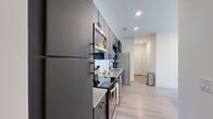 Located in Houston's vibrant Montrose neighborhood, this thoughtfully designed 3-bedroom, 3-bathroom residence offers a modern aesthetic throughout its efficiently planned single-floor layout. The galley-style kitchen is a standout, featuring sleek dark cabinetry with matte black hardware, granite countertops, white subway tile backsplash, and a full suite of stainless steel appliances including a refrigerator, range, microwave, and dishwasher. Light wood-look flooring flows seamlessly from the kitchen into the adjoining living room, which is bathed in natural light through oversized French doors that open to a private balcony with outdoor views. The bedrooms continue the bright, airy theme, each finished with crisp white walls and several featuring their own French door balcony access. The primary bedroom offers a comfortable, well-proportioned retreat. All three bathrooms are finished with granite-topped white vanities, undermount sinks, and matte black fixtures, with tub-shower combinations clad in clean vertical white tile. A central hallway efficiently connects all rooms, while recessed lighting throughout maintains a polished, contemporary feel. This residence delivers a clean, modern living experience in one of Houston's most sought-after urban neighborhoods.