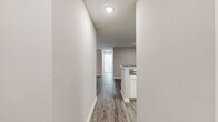 Located at 100 Camellia Ln in Stonecrest, Georgia, this single-story home offers a thoughtfully designed layout with three bedrooms, two bathrooms, and a dedicated laundry area. The interior is finished with neutral warm-toned walls and durable wood-look flooring throughout the main living areas, creating a cohesive and modern aesthetic.

The kitchen is a standout feature, boasting crisp white shaker-style cabinetry, granite-look countertops, a stainless steel sink, and black appliances including a range and dishwasher. It connects seamlessly to the living room, which is brightened by natural light from a door leading to an outdoor deck and features a ceiling fan overhead.

The bedrooms are carpeted for comfort and include windows that frame views of surrounding greenery, lending a peaceful, natural ambiance. Three closets—including walk-in closet space with wire shelving—provide ample storage throughout. The bathrooms are finished with wood-look flooring, granite-topped vanities, and a tiled tub-shower combination with brushed nickel fixtures.

A central hallway connects all areas of the home efficiently. The overall design emphasizes clean lines, practical finishes, and a neutral palette that creates a bright, move-in-ready living environment.