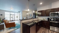 Located at 19112 East Alki Avenue in Spokane Valley, Washington, this single-story unit offers a well-designed open-concept layout that connects the kitchen, dining, and living areas into one cohesive space. The kitchen is a standout feature, showcasing rich dark-stained cabinetry, dark granite countertops, a subway tile backsplash, stainless steel appliances including a dishwasher, microwave, and refrigerator, and pendant lighting above a peninsula that provides additional counter space and visual separation from the living area. Wood-style plank flooring runs throughout the main living spaces, adding warmth and continuity.

The dining area is positioned near a window and entry door, with a chandelier overhead that adds an elegant touch. The living room is bright and comfortable, benefiting from a large sliding glass door that invites natural light and outdoor access. The bedroom features plush carpet, a wide window with outdoor views, and a baseboard heating unit. The bathroom includes wood-look flooring, a soaking tub, and clean, neutral finishes throughout. The overall design balances modern aesthetics with functional, everyday livability.