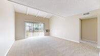 Located at 1919 E Birch St in Brea, CA, this single-floor, three-bedroom, one-bathroom home offers a thoughtfully arranged layout with warm, neutral tones and comfortable finishes throughout. The living area is a standout feature, boasting vaulted ceilings with exposed white wooden beams and a textured ceiling that adds architectural character. Large sliding glass doors flood the space with natural light and open directly onto a private balcony, offering views of the surrounding greenery. Soft carpeting extends through the living areas and bedrooms, creating a cohesive and inviting atmosphere. The generously sized primary bedroom provides ample space and includes a mirrored closet, while the additional bedrooms are well-proportioned and also feature closet storage with built-in shelving. A ceiling fan adds comfort to one of the secondary bedrooms. The kitchen is functional and well-equipped, featuring white cabinetry with brushed nickel hardware, dark granite-style countertops, wood-look vinyl flooring, and black appliances including a range with overhead hood and a full-size refrigerator. The bathroom is cleanly appointed with a white vanity, granite-style countertop, wood-look tile flooring, and a full bathtub with shower. A hallway connects all rooms, providing an efficient and comfortable flow throughout the home.
