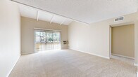 Located at 1919 E Birch St in Brea, CA, this single-floor, three-bedroom, one-bathroom home offers a thoughtfully arranged layout with warm, neutral tones and comfortable finishes throughout. The living area is a standout feature, boasting vaulted ceilings with exposed white wooden beams and a textured ceiling that adds architectural character. Large sliding glass doors flood the space with natural light and open directly onto a private balcony, offering views of the surrounding greenery. Soft carpeting extends through the living areas and bedrooms, creating a cohesive and inviting atmosphere. The generously sized primary bedroom provides ample space and includes a mirrored closet, while the additional bedrooms are well-proportioned and also feature closet storage with built-in shelving. A ceiling fan adds comfort to one of the secondary bedrooms. The kitchen is functional and well-equipped, featuring white cabinetry with brushed nickel hardware, dark granite-style countertops, wood-look vinyl flooring, and black appliances including a range with overhead hood and a full-size refrigerator. The bathroom is cleanly appointed with a white vanity, granite-style countertop, wood-look tile flooring, and a full bathtub with shower. A hallway connects all rooms, providing an efficient and comfortable flow throughout the home.