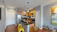 Located on Lindell Boulevard in the heart of St. Louis, Unit 2053 is a thoughtfully designed single-floor residence that balances style and functionality throughout. The open-concept kitchen is equipped with warm maple cabinetry, dark granite countertops, stainless steel appliances including a refrigerator and microwave, and a peninsula with bar seating illuminated by sleek pendant lights — making it an inviting hub for cooking and casual dining. Rich hardwood flooring flows seamlessly from the kitchen into the living area, where cool blue-gray walls create a calm, contemporary backdrop. The living room offers generous space for entertaining and connects naturally to a charming bay window nook, ideal for a dining set, that draws in ample natural light. Two bedrooms provide comfortable retreats: one features plush carpeting, a bold accent wall, and a window for natural light, while the second includes hardwood flooring and a bright window with outdoor views. The bathroom is finished with tile flooring and a full soaking tub with tile surround. Throughout the unit, consistent blue-gray paint tones, hardwood floors, and modern fixtures create a cohesive and contemporary living environment.